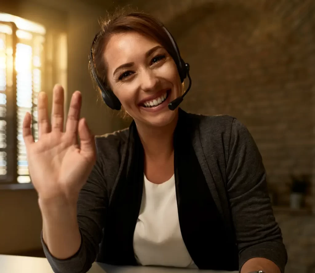 Young happy female business owner waving while video call with a customer to create an excellent customer experience