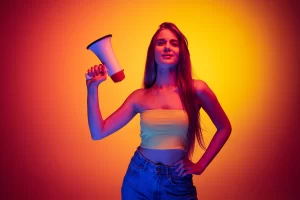 portrait young beautiful woman holding megaphone isolated red yellow background neon light